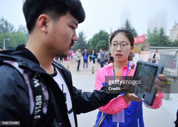 Staff member checks the identity of a student entering a school to take the 2018 college entrance exam of China, or the "Gaokao", in Qingdao in...