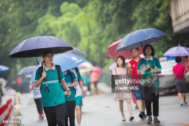 Candidates enter an exam site with umbrellas for the National College Entrance Examination at Zhong Yuan High School on June 7, 2018 in Guangzhou,...