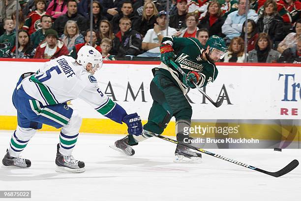 Guillaume Latendresse of the Minnesota Wild shoots the puck past the outstretched stick of Christian Ehrhoff of the Vancouver Canucks during the game...
