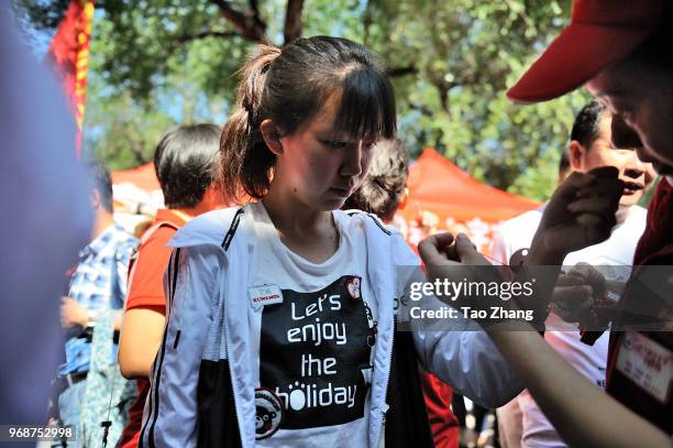 People wear charm bracelet outside of the school for children before the first subject of the China's Annual College Entrance Exams on June 7, in...