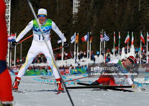 Anna Haag of Sweden celebrates her 2nd place finish in the Ladies' 15 km Pursuit as Justyna Kowalczyk of Poland falls to the ground in third place on...