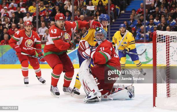 Viktor Kostiuchenok and goalkeeper Andrei Mezin of Belarus shield the puck from Samuel Pahlsson of Sweden during the ice hockey men's preliminary...