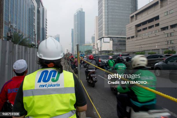 An official of Jakarta's MRT project walks along the construction site in Jakarta on June 7 2018 as the right side showing heavy traffic. - Deep...