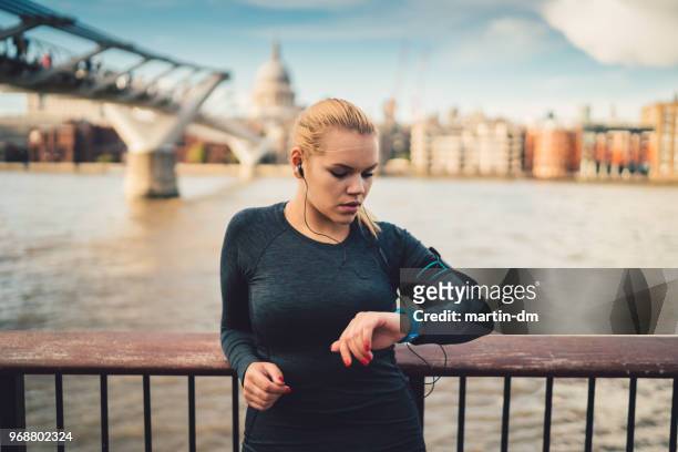 sportswoman in uk checking pulse on smart watch during workout - pedometer stock pictures, royalty-free photos & images