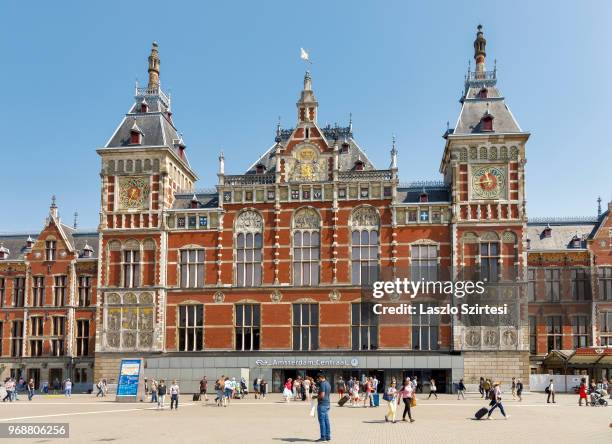 Pedestrians and tourists walk in front of the Main Station on May 27, 2018 in Amsterdam, Netherlands. This is the best-known meeting point of the...