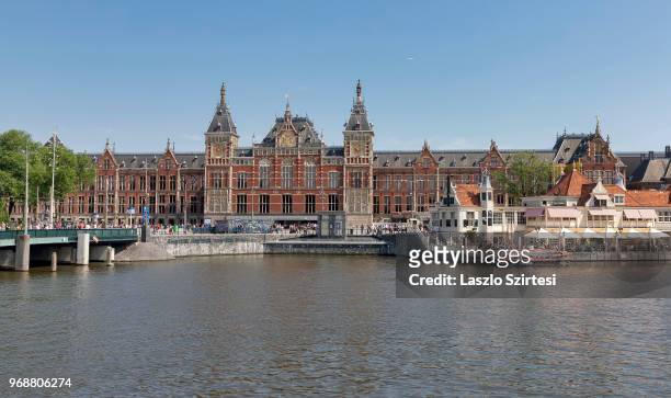 Pedestrians and tourists walk in front of the Main Station on May 27, 2018 in Amsterdam, Netherlands. This is the best-known meeting point of the...