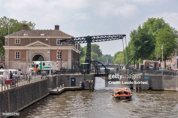 Sightseeing boat passes under a moveable bridge of Nieuwe Herengracht Canal on May 30, 2018 in Amsterdam, Netherlands. In Amsterdam can be found...