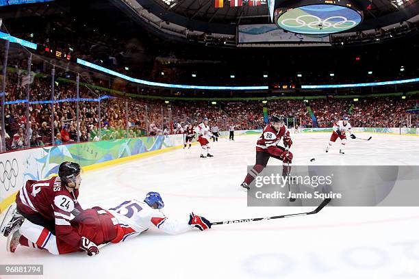 Mikelis Redlihs of Latvia and Jan Hejda of Czech Republic fall to the ice during the ice hockey men's preliminary game between Czech Republic and...