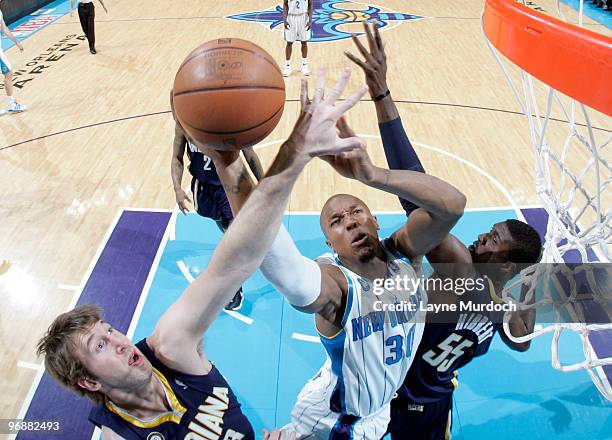 David West of the New Orleans Hornets shoots between Troy Murphy and Roy Hibbert of the Indiana Pacers on February 19, 2010 at the New Orleans Arena...