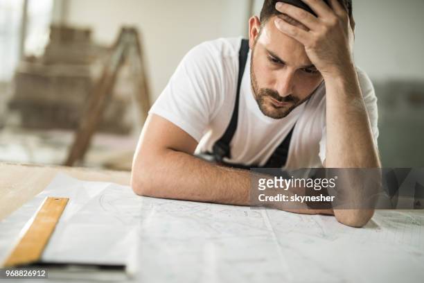 frustrated manual worker having problems with blueprints at construction site. - frustrated workman stock pictures, royalty-free photos & images