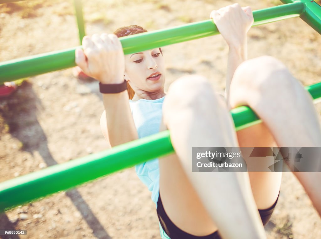 Strong athletic woman exercising in outdoor gym.
