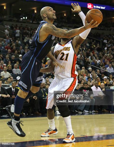 Carlos Boozer of the Utah Jazz shoots against Ronny Turiaf of the Golden State Warriors during an NBA game at Oracle Arena at Oracle Arena on...