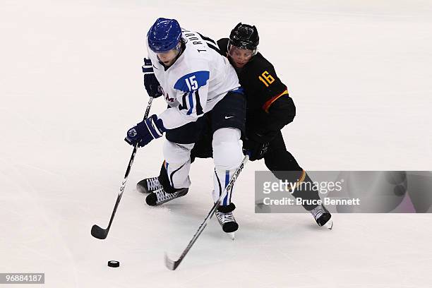 Michael Wolf of Germany challenges Tuomo Ruutu of Finland for the puck during the ice hockey men's preliminary game between Finland and Germany on...