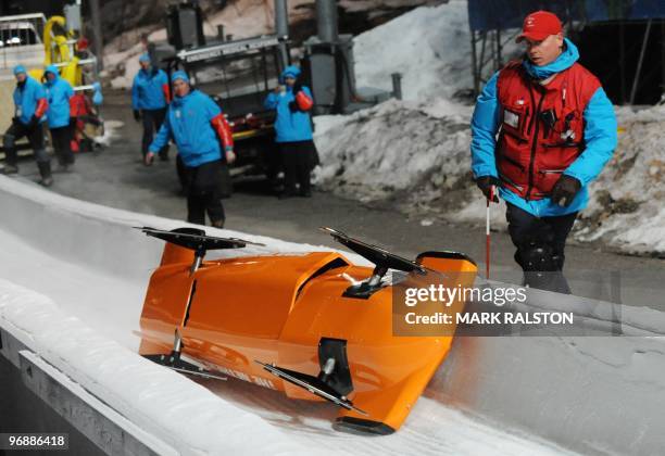 The Dutch team led by pilot Esme Kamphuis, are helped by track staff after crashing during the training session for the women's Two-Man Bobsleigh at...