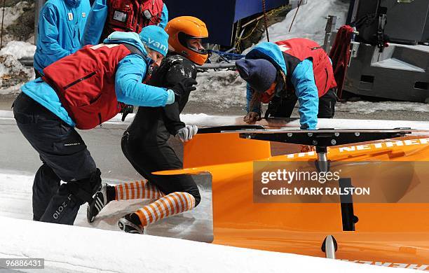 The Dutch team led by pilot Esme Kamphuis, are helped by track staff after crashing during the training session for the women's Two-Man Bobsleigh at...