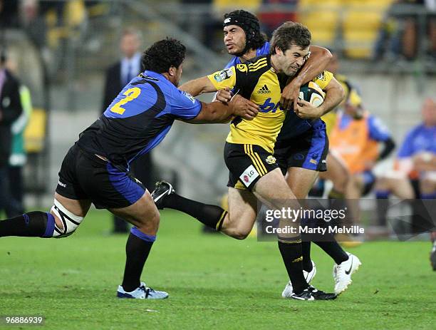 Conrad Smith of the Hurricanes is tackled by Pekahou Cowan and Josh Tatupu of the Force during the round two Super 14 match between the Hurricanes...