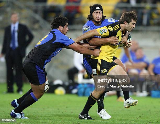 Conrad Smith of the Hurricanes is tackled by Pekahou Cowan and Josh Tatupu of the Force during the round two Super 14 match between the Hurricanes...