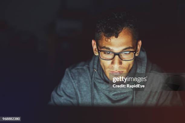 handsome man working on computer at night looks serious - staring at screen stock pictures, royalty-free photos & images
