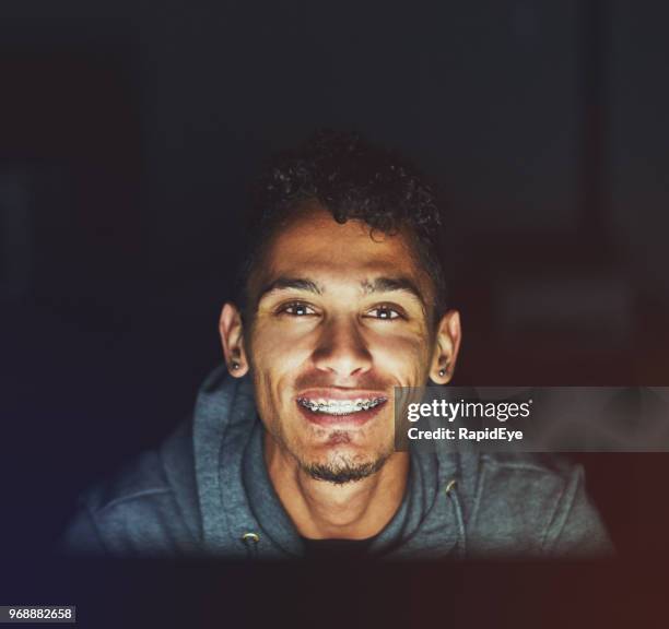 handsome man working on computer at night smiles - 2017 common good forum stock pictures, royalty-free photos & images