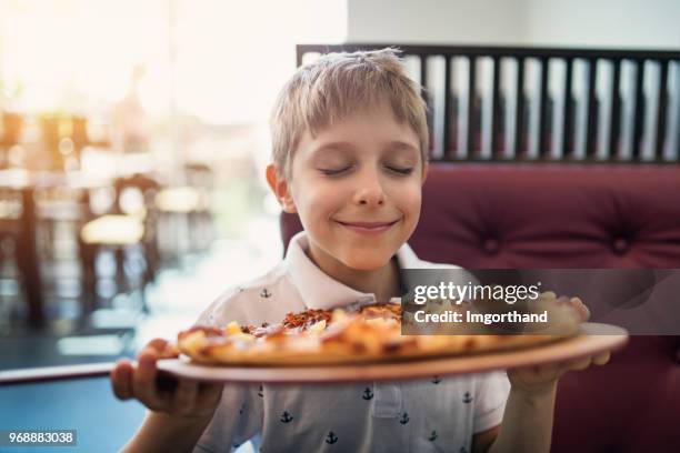 kleiner junge riechen pizza im restaurant - restaurant kids stock-fotos und bilder