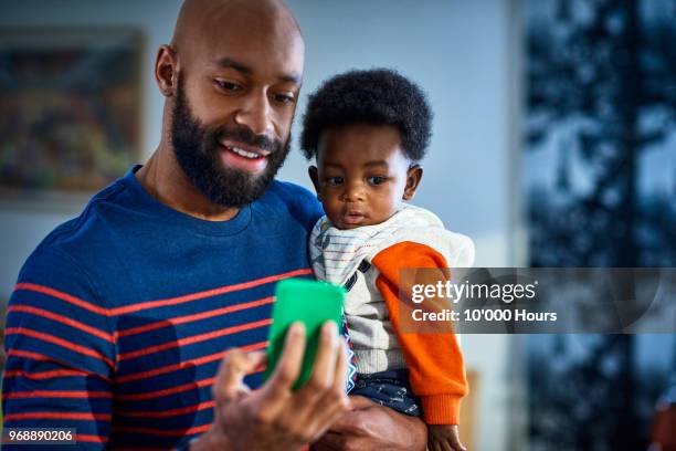 man with baby son (6-11 months) at home - homemaker stock-fotos und bilder