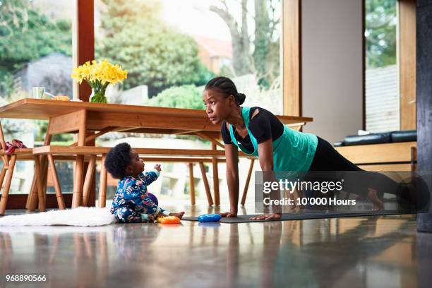 baby boy assisting mother exercising - busy woman stockfoto's en -beelden