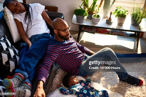 parents with baby son resting - couple sleeping on sofa stock pictures, royalty-free photos & images