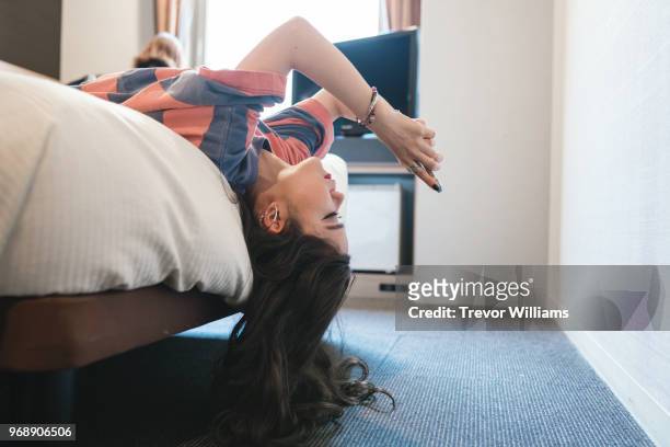woman looking at a smart phone on a bed - child phone stockfoto's en -beelden