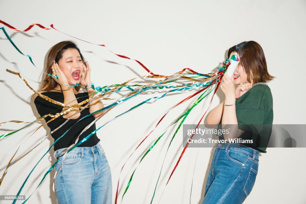 Young women surprising her friend with a party cracker