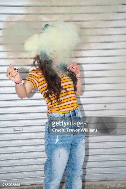 Young woman whose face is obscured by a cloud of smoke