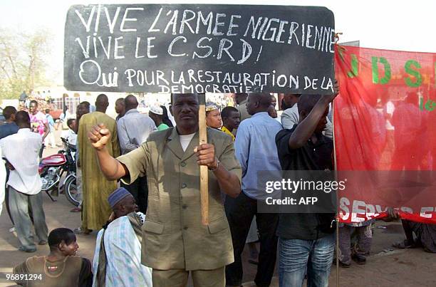 Man holds a banner reading 'Long life to Niger's army. Long life to CSRD. Yes to the restauration of democracy' during a rally in Niger's capital...