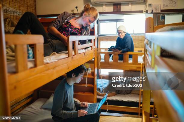 寮の若い旅行者スタイルのバックパッカーのホステルのラップトップ コンピューターを使用して - bunk beds for 3 ストックフォトと画像