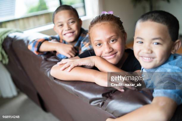 niños que se inclinan en el sofá y mirando a cámara. - maorí fotografías e imágenes de stock