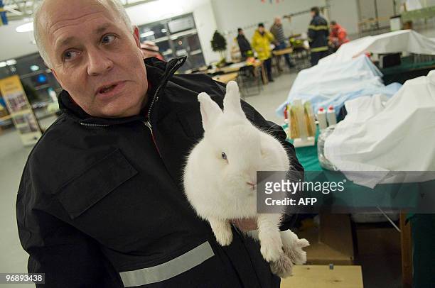 Exhibition organizer Johnny Johansson carries a rabbit following the collapse of the roof of a tennis hall in Rosvalla in Nykoping, February 20,...