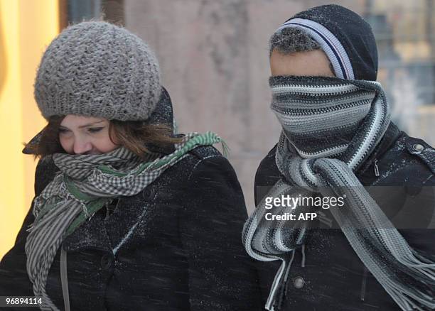 Man and a woman cover their faces to protect themselves against snow and strong winds in Stockholm, Sweden, February 20, 2010. Heavy snow took...