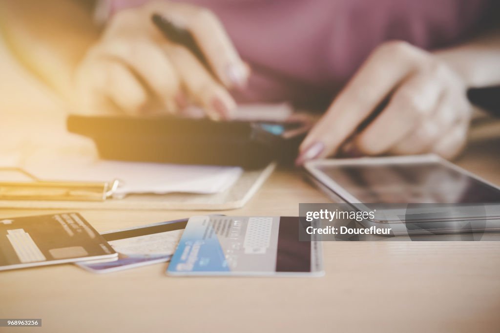 Woman hand calculating her expenses and debt from credit cards with smart phone