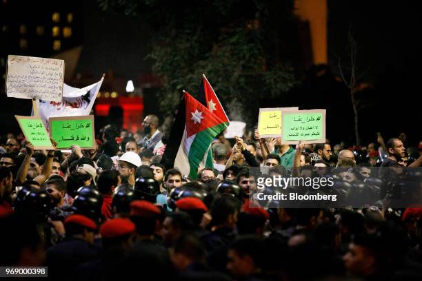 Protesters wave Jordanian national flags and hold banners during a demonstration against a draft income tax law near the prime minister's office in...