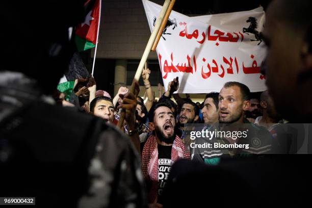 Protesters wave Jordanian national flags and hold banners during a demonstration against a draft income tax law near the prime minister's office in...