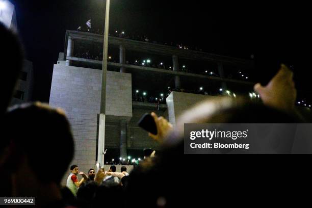 Protesters shout slogans and illuminate their mobile phones during a demonstration against a draft income tax law near the prime minister's office in...