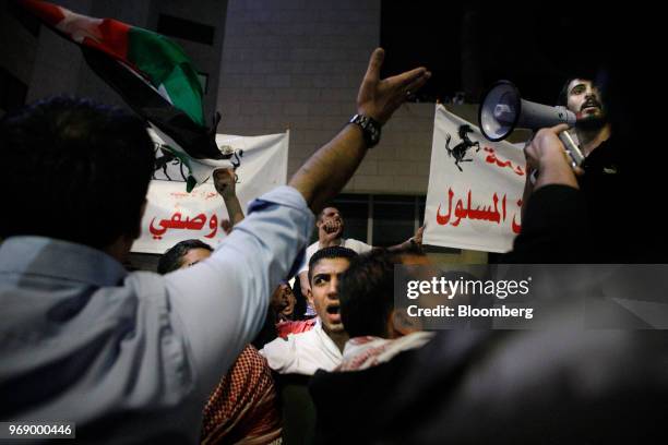 Protesters wave Jordanian national flags and hold banners during a demonstration against a draft income tax law near the prime minister's office in...