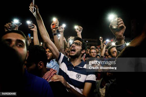 Protesters shout slogans and illuminate their mobile phones during a demonstration against a draft income tax law near the prime minister's office in...