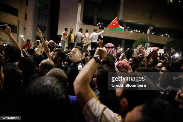 Protesters wave Jordanian national flags and illuminate their mobile phones during a demonstration against a draft income tax law near the prime...