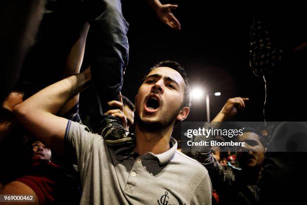 Protester stands on another's shoulder to shout slogans to the crowd during a demonstration against a draft income tax law near the prime minister's...