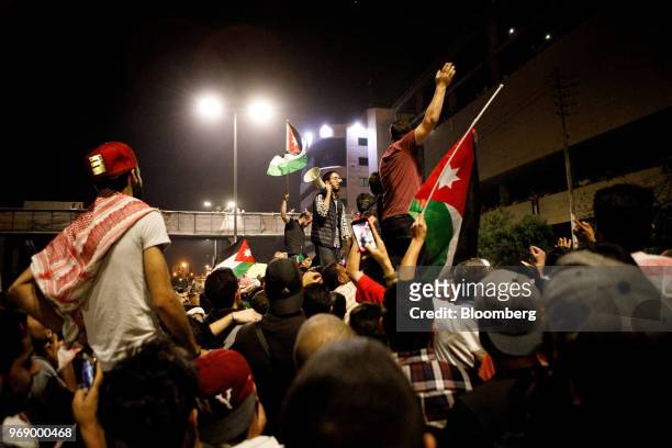 Protesters wave Jordanian national flags and shout slogans during a demonstration against a draft income tax law near the prime minister's office in...