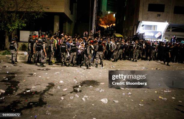 Anti riot police and security forces block the path of protesters during a demonstration against a draft income tax law near the prime minister's...