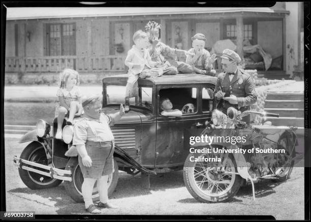 American child actress Mary Ann Jackson at the wheel of a miniature car with Pete the Pup, as she talks to a traffic cop, Southern California, 1930....