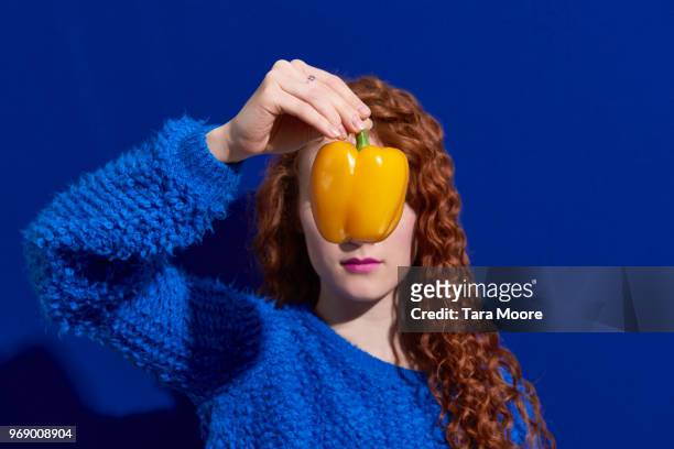 woman holding yellow pepper in front of face - gele paprika stockfoto's en -beelden