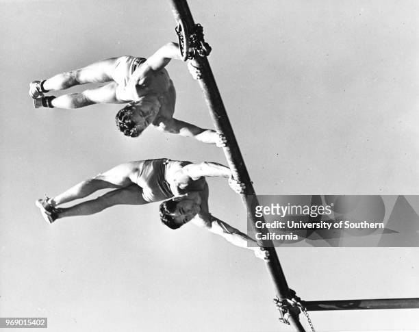 Two men practicing gymnastics from one of the playground bars, Los Angeles, California, early to mid twentieth century.