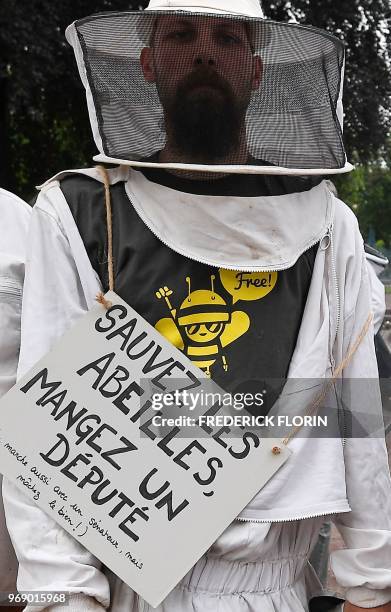 Beekeeper with a placard on his chest reading "Save a bee, eat a MP" stands during a demonstration in Strasbourg, eastern France, on June 7, 2018. -...