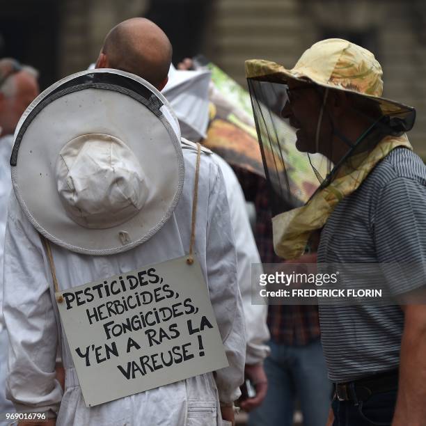 Beekeeper with a placard on his back reading "Pesticides, herbicides, fungicides. Enough!" gathers with others during a demonstration in Strasbourg,...